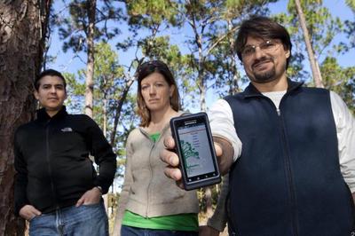 At the Natural Areas Teaching Lab on the University of Florida campus, Emilio Bruna, a UF associate professor of wildlife ecology and conservation, left, and graduate students Shelly Johnson and Matt Palumbo, display the Android app Bruna’s fall 2010 plant-animal interaction class created and recently released. More than a semester in the making, the app helps users identify and locate more than 35 tree species on the UF campus. Users can download it for free at the Android Market – Dec. 2, 2011. (UF/IFAS photo by Tyler L. Jones)